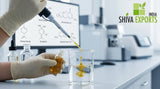 A close-up of a chemist using a micropipette to drop a golden botanical extract into a clear beaker containing alcohol, clean lab background with a computer screen showing chemical structures