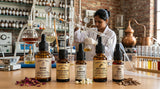 Close-up shot of various essential oil bottles with labels in a laboratory setting in Kannauj, India. Focus on the detail of the oils and the scientific equipment in the background.