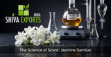 Macro photograph of fresh night-blooming Jasmine Sambac blossoms on a dark, reflective slate surface, with laboratory glassware containing a golden-amber extract in the background, clean clinical lighting